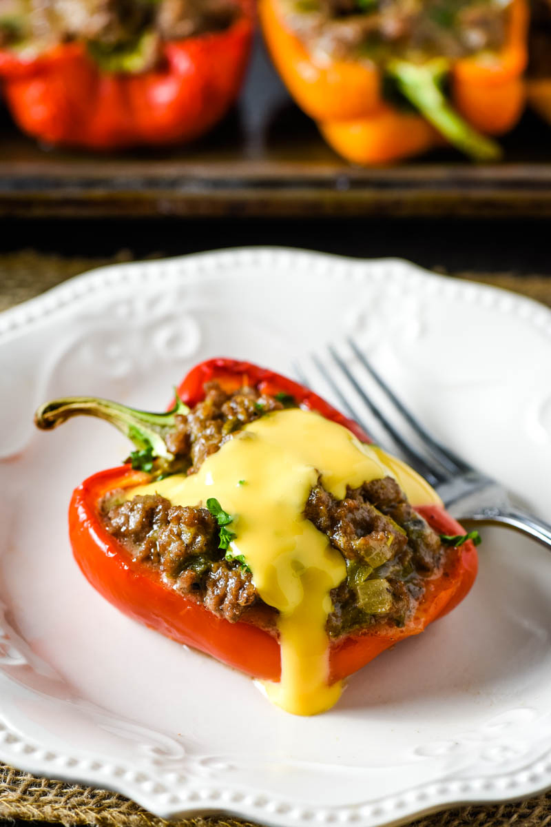 cheesesteak stuffed pepper with Cheez Whiz on top, on white plate with fork