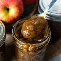 spooning stovetop apple butter out of glass jelly jar