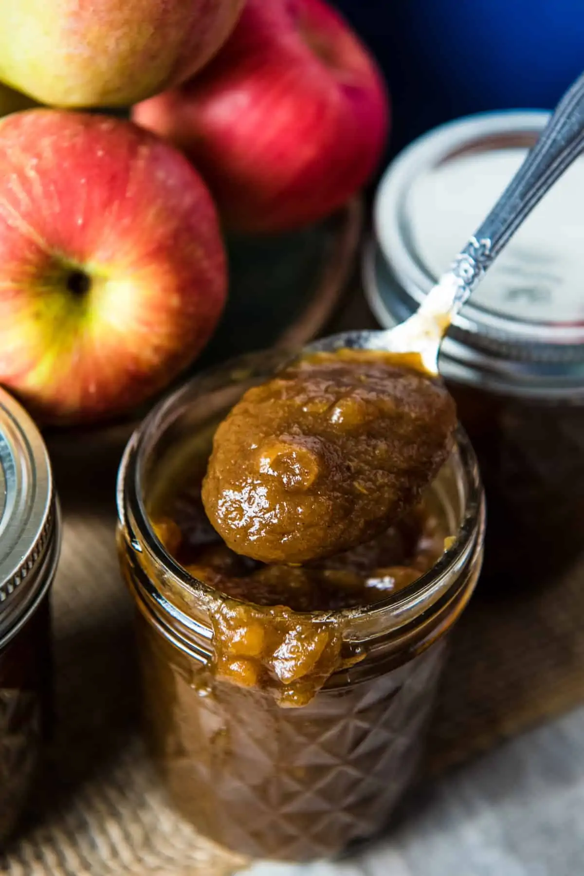 spoonful of easy stovetop apple butter over jelly jar with drips of apple butter on rim