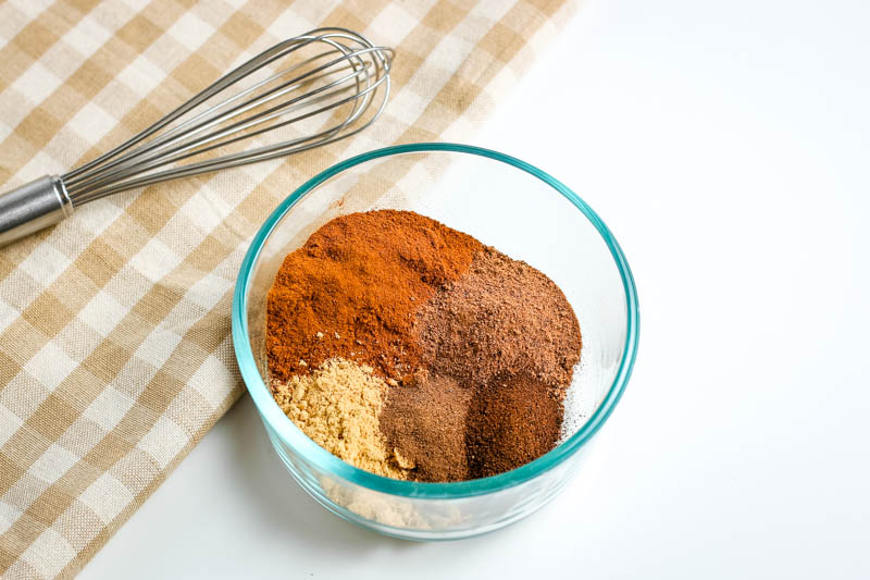 small glass bowl of pumpkin pie spice ingredients with whisk