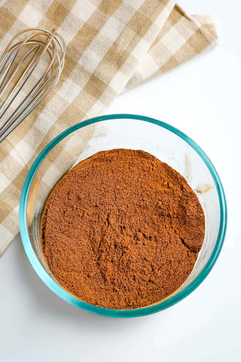 small glass bowl of pumpkin spice mix with whisk