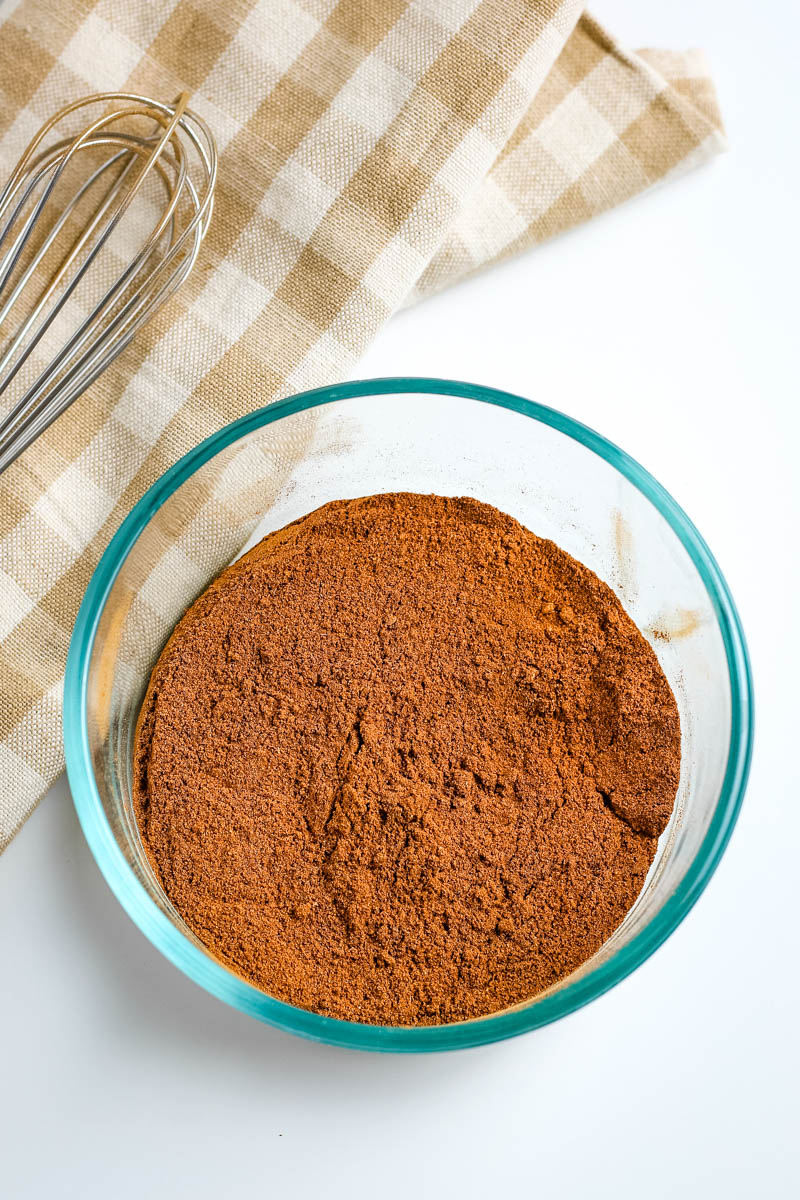 small glass bowl of pumpkin spice mix with whisk