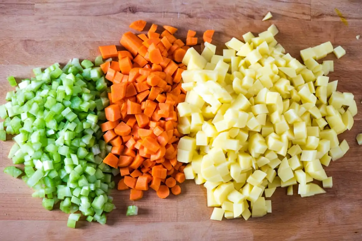 chopped fresh celery, carrots, and potatoes for hearty CrockPot vegetable soup on wooden cutting board
