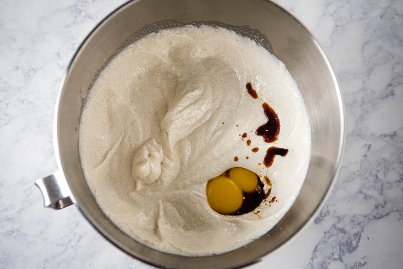 egg yolks and vanilla extract with butter and sugar mixture in KitchenAid mixing bowl
