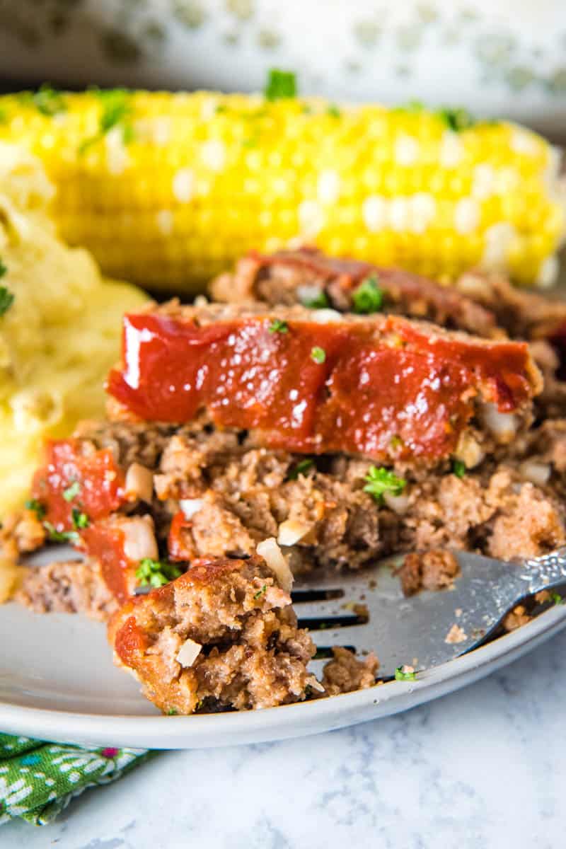 bite of classic meatloaf on fork, on gray plate