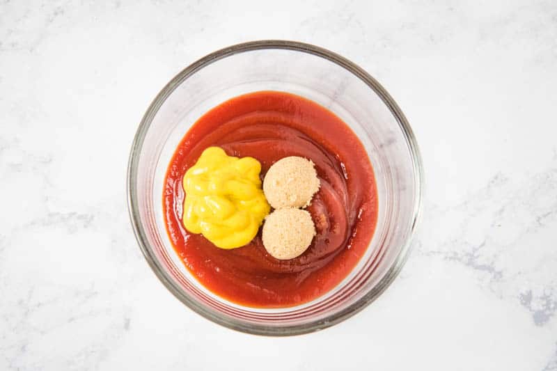 meatloaf sauce ingredients, including ketchup, mustard, and brown sugar in small glass mixing bowl