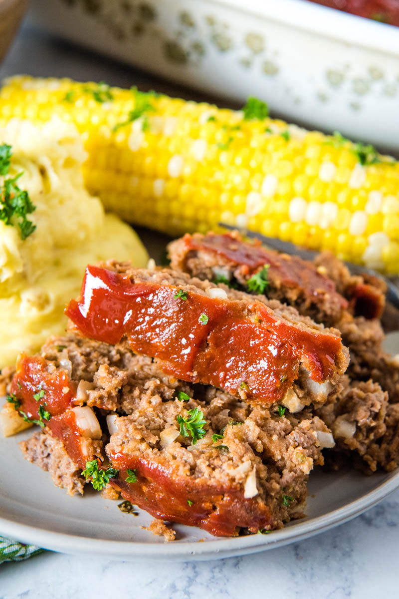 slices of traditional meatloaf with meatloaf sauce topping on gray plate