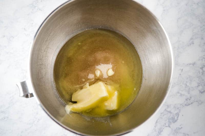Butter, canola oil, and sugar in KitchenAid mixing bowl on white countertop