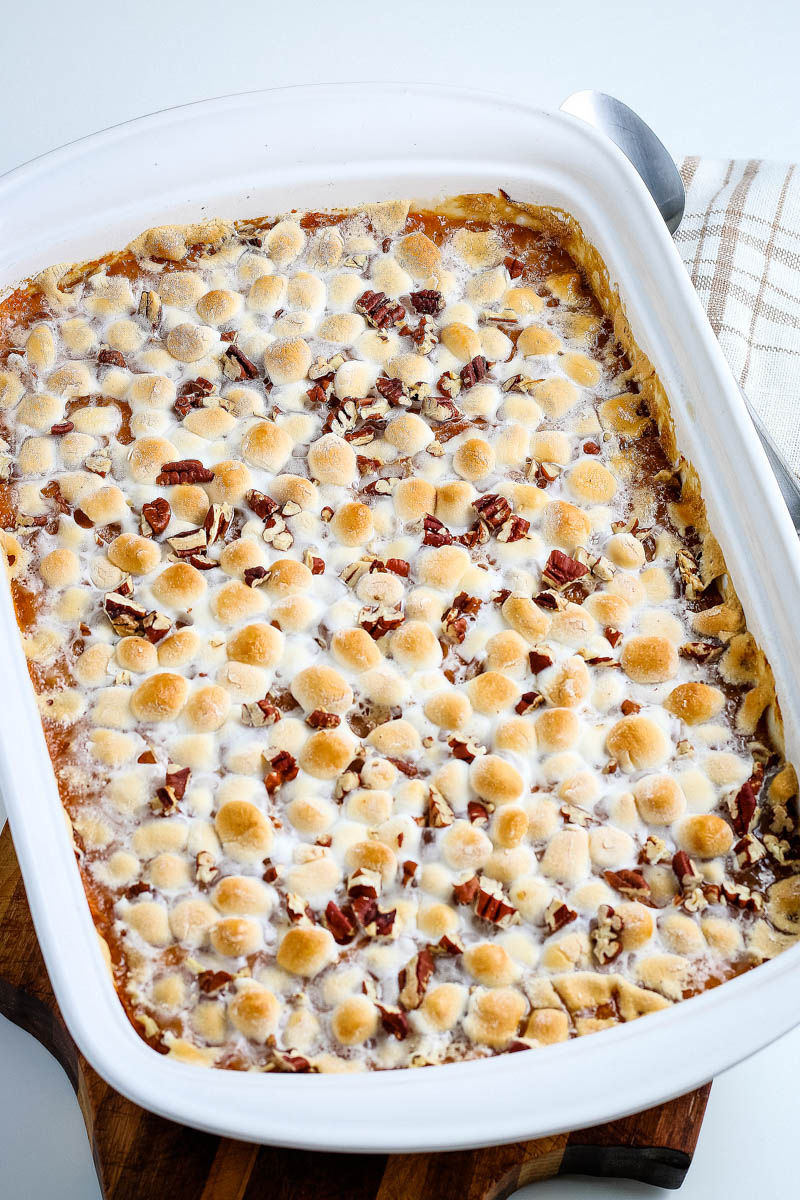 baked sweet potato casserole with marshmallows and pecans in white casserole dish