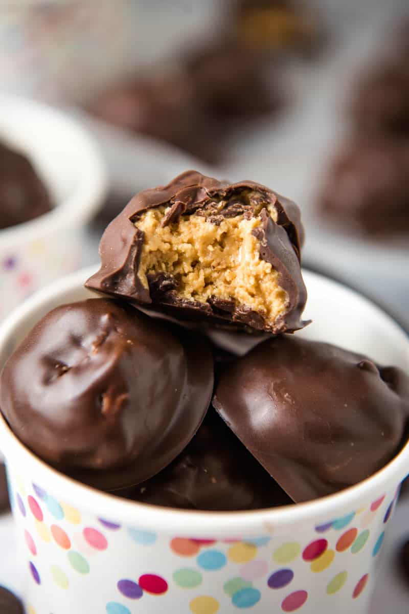 chocolate peanut butter balls with Rice Krispies piled up in rainbow polka dot snack cup with bite out of top peanut butter ball