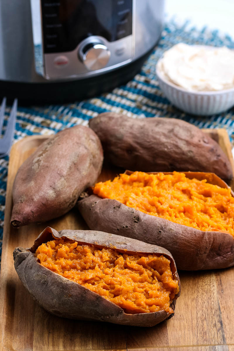 steamed sweet potatoes cooked in the Instant Pot, sitting on wooden cutting board and sliced open