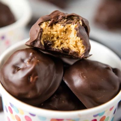 Rice Krispie peanut butter balls with a bite taken out in a small paper cup