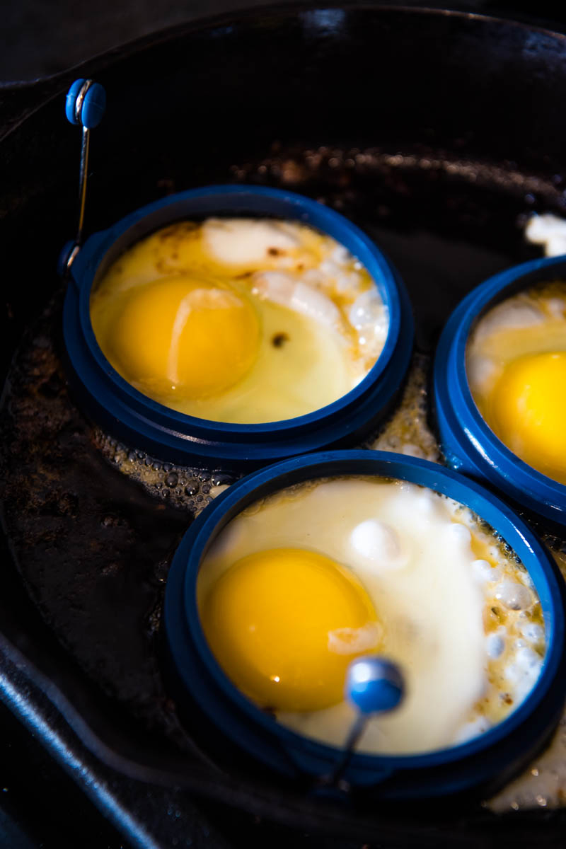 frying eggs in rounded egg rings in cast iron skillet