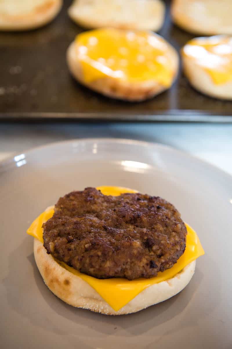 sausage patty on top of melted American cheese on English muffin, on gray plate