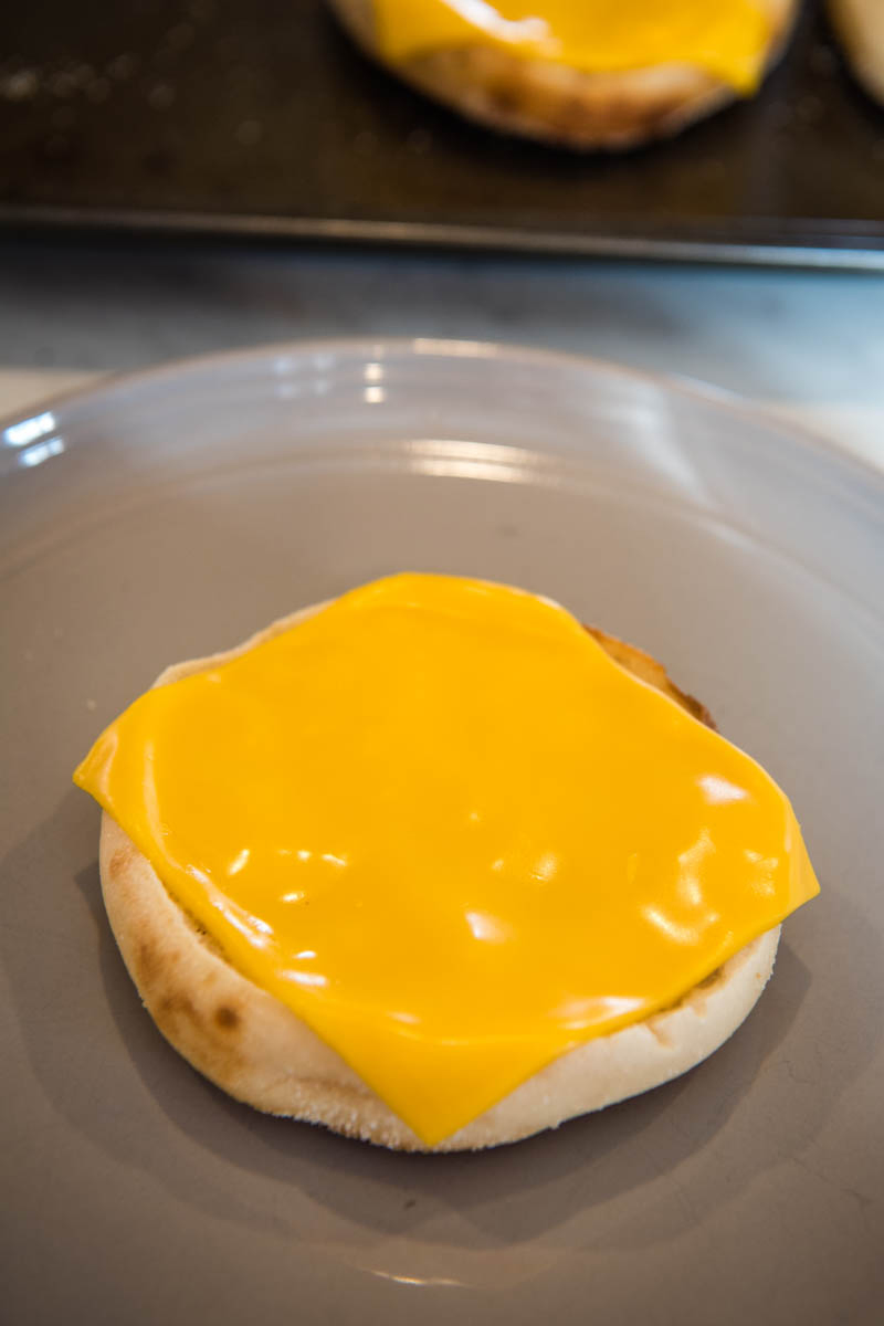 melted slice of American cheese on English muffin bottom, on gray plate