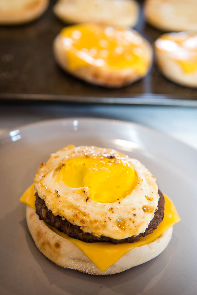 assembling sausage egg McMuffin on gray plate