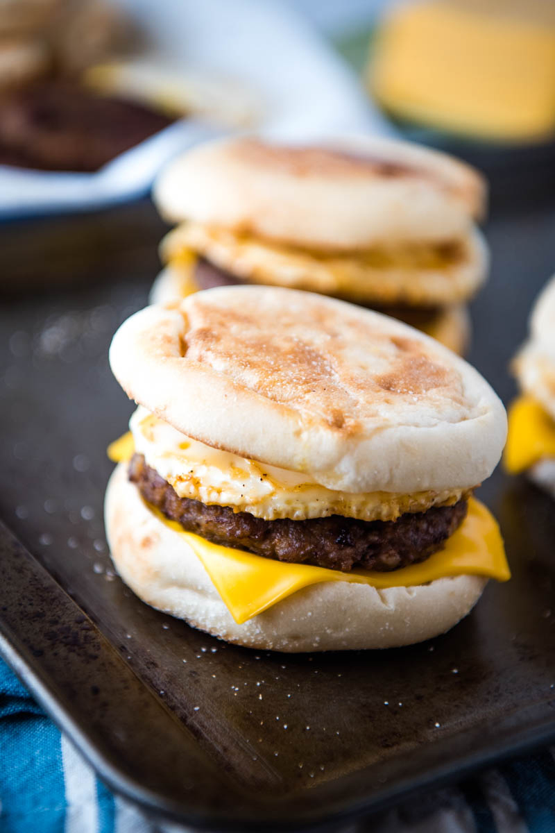 sausage and egg McMuffin sandwich on baking sheet with more breakfast sandwiches