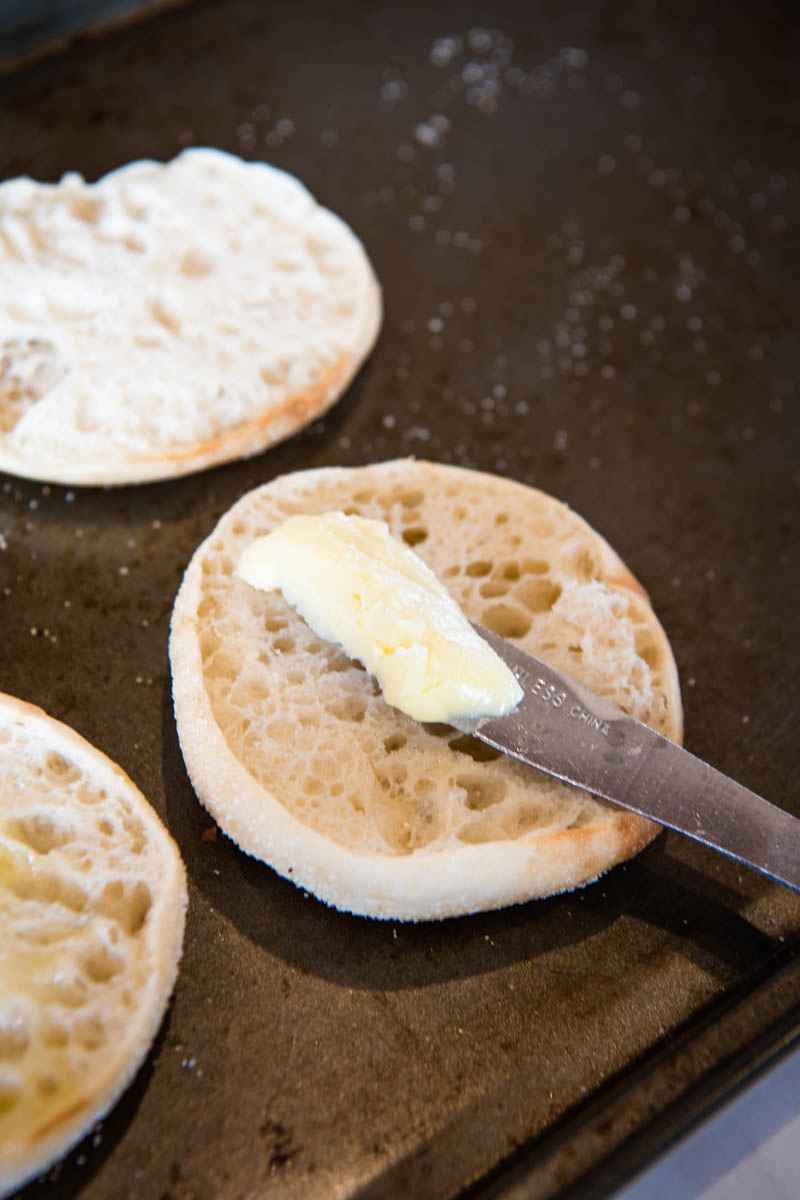 spreading butter on toasted English muffins with table knife