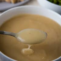 spooning creamy chicken gravy without drippings out of a small white decorative bowl