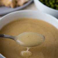 spoonful of easy chicken gravy from bouillon over white bowl full of gravy