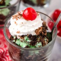 mint chocolate chip grasshopper sundae topped with a cherry in a small glass serving cup