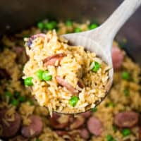 large wooden spoonful of kielbasa and rice after cooking
