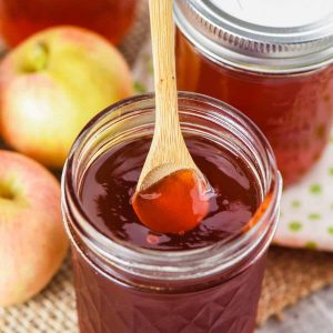 small wooden spoon in half pint jar of apple jelly recipe with Gala apples
