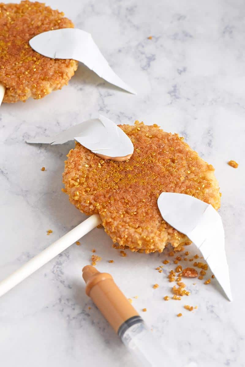 attaching Golden Snitch wings to cookies with melted candy melts