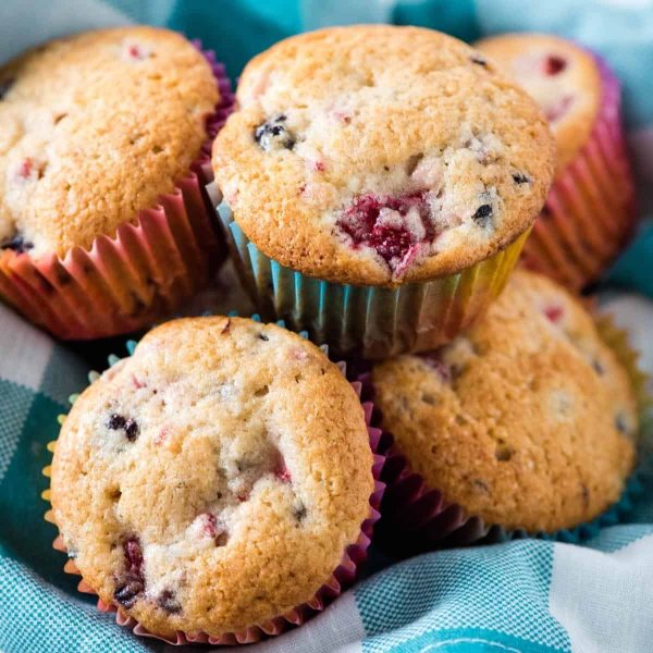 pile of blackberry strawberry muffins on teal checkered linen