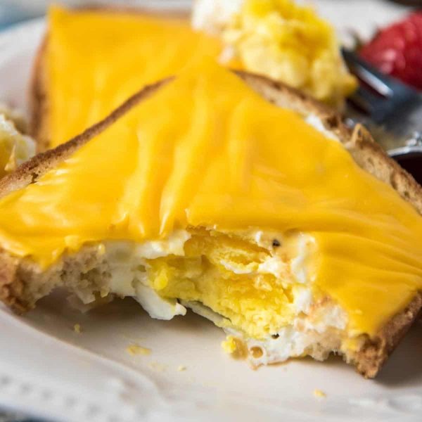 sliced eggs in a nest with cheese on white plate