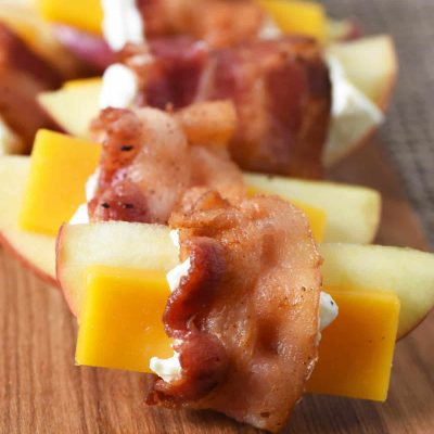 bacon wrapped apples with cheese on wooden cutting board