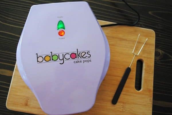 Babycakes cake pop maker with fork on wood cutting board
