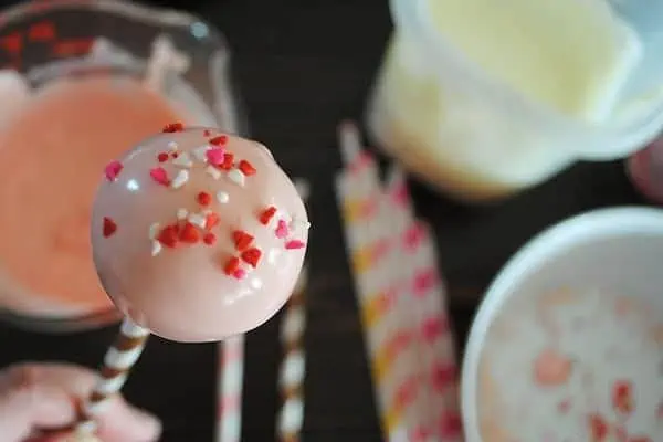 pink Valentine's Day cake pop with tiny heart sprinkles on top