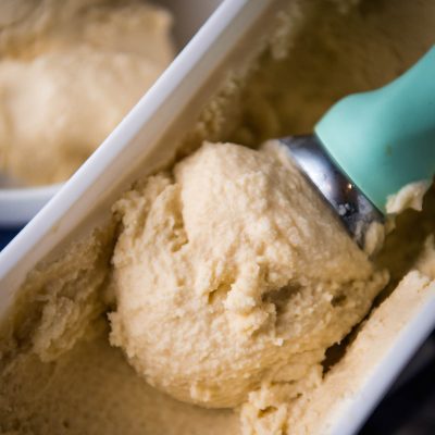 mint green scoop with raw milk ice cream in white ice cream container