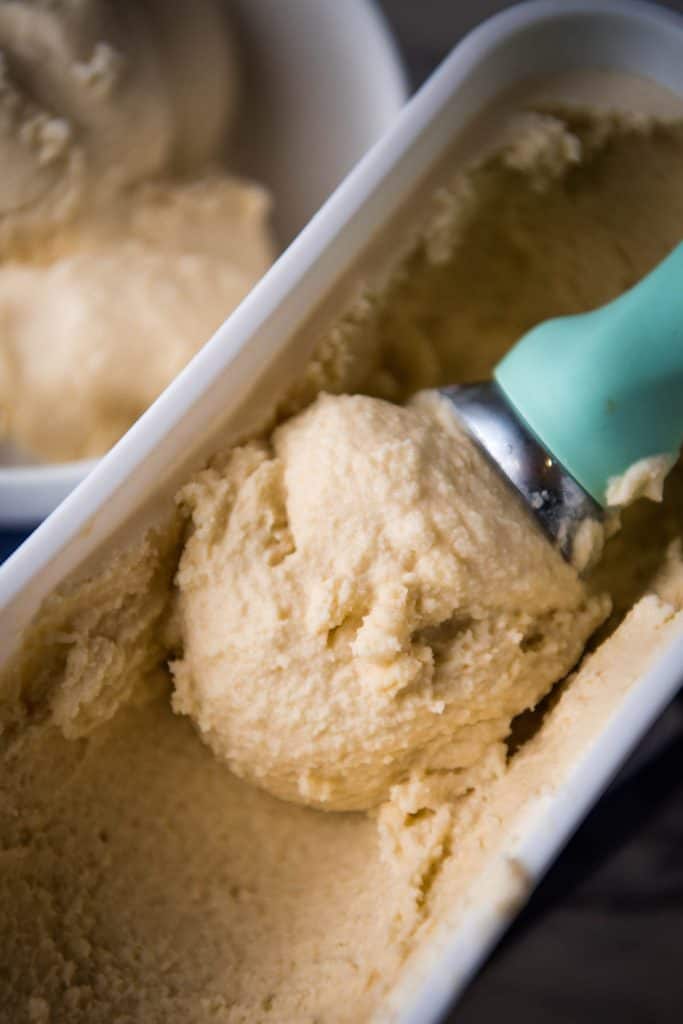 mint green scoop with raw milk ice cream in white ice cream container