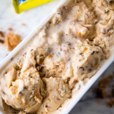 homemade butterfinger ice cream in white rectangular storage container on a marbled white countertop