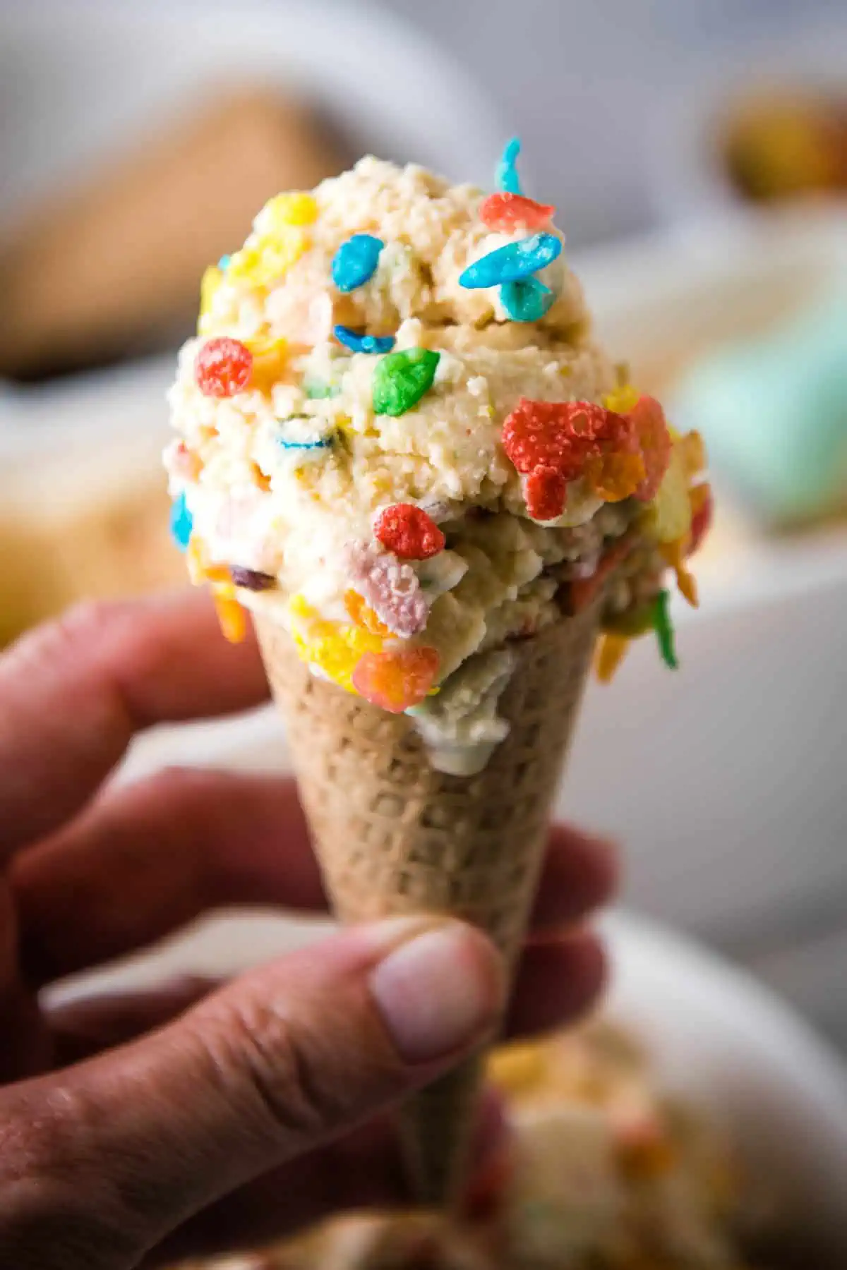hand holding fruity pebble ice cream cone