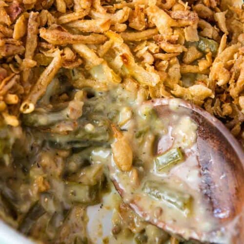 large white baking dish full of homemade green bean casserole with a large wooden spoon