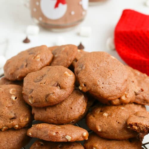 hot chocolate cookies piled up on silver wire cooling rack on white countertop
