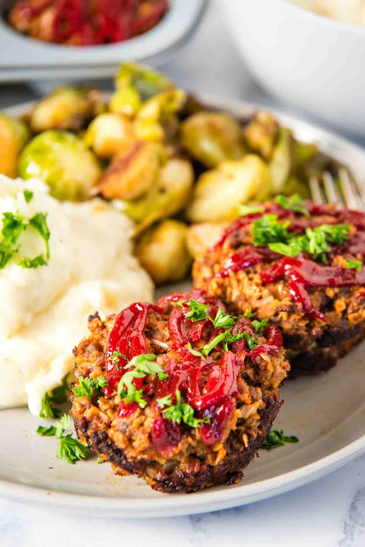 meatloaf muffins served up with mashed potatoes and green beans on a small white plate