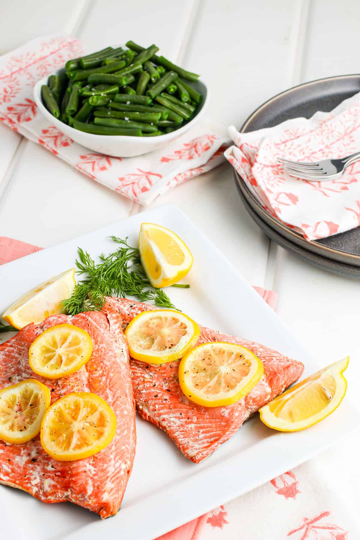 Insta Pot salmon lined out on a decorative white plate with fresh lemon slices on top and fresh dill sprigs on the side