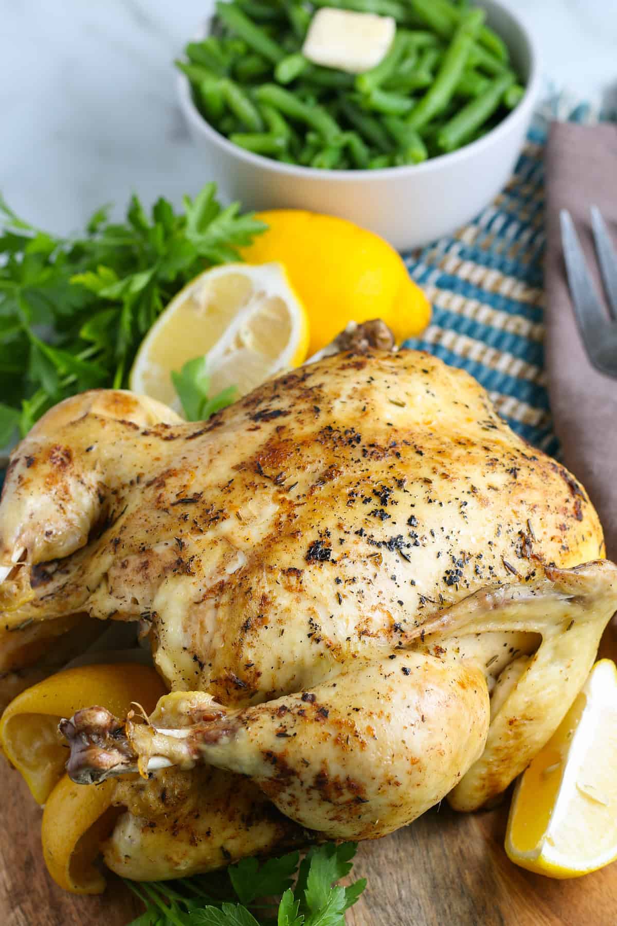 whole chicken with lemons and peppers fresh out of the Instant Pot on a large wooden cutting board