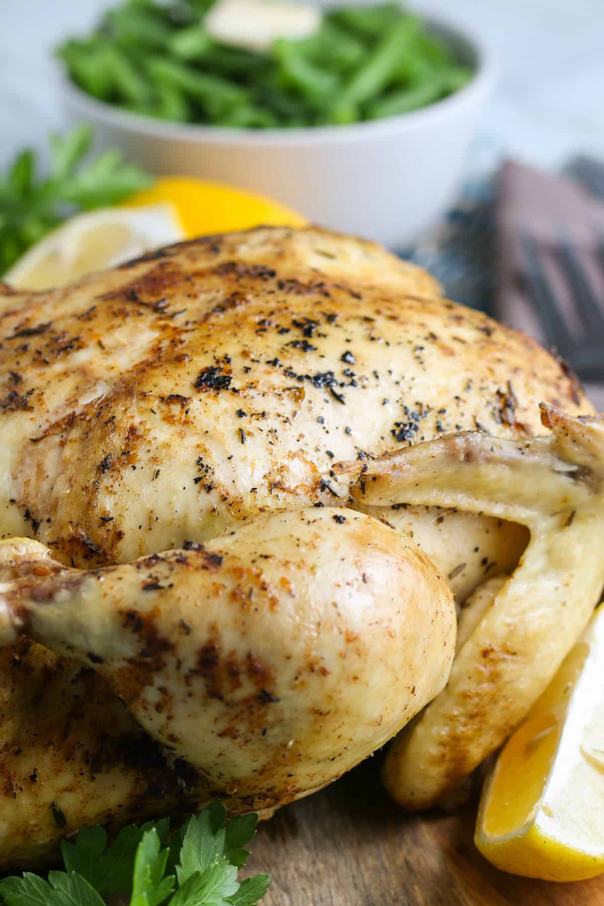 juicy whole chicken stuffed with lemons and peppers, and ready to slice and eat on a large wooden cutting board
