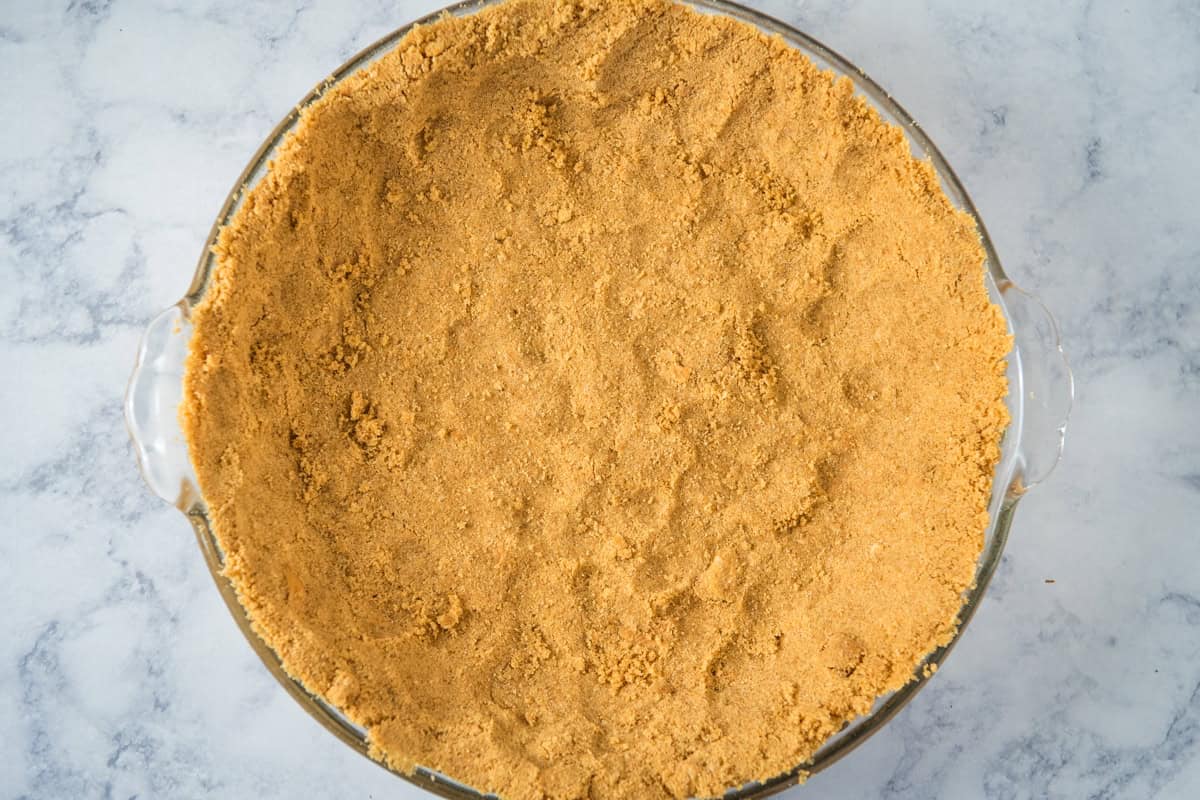 homemade graham cracker crust in a large glass pie plate
