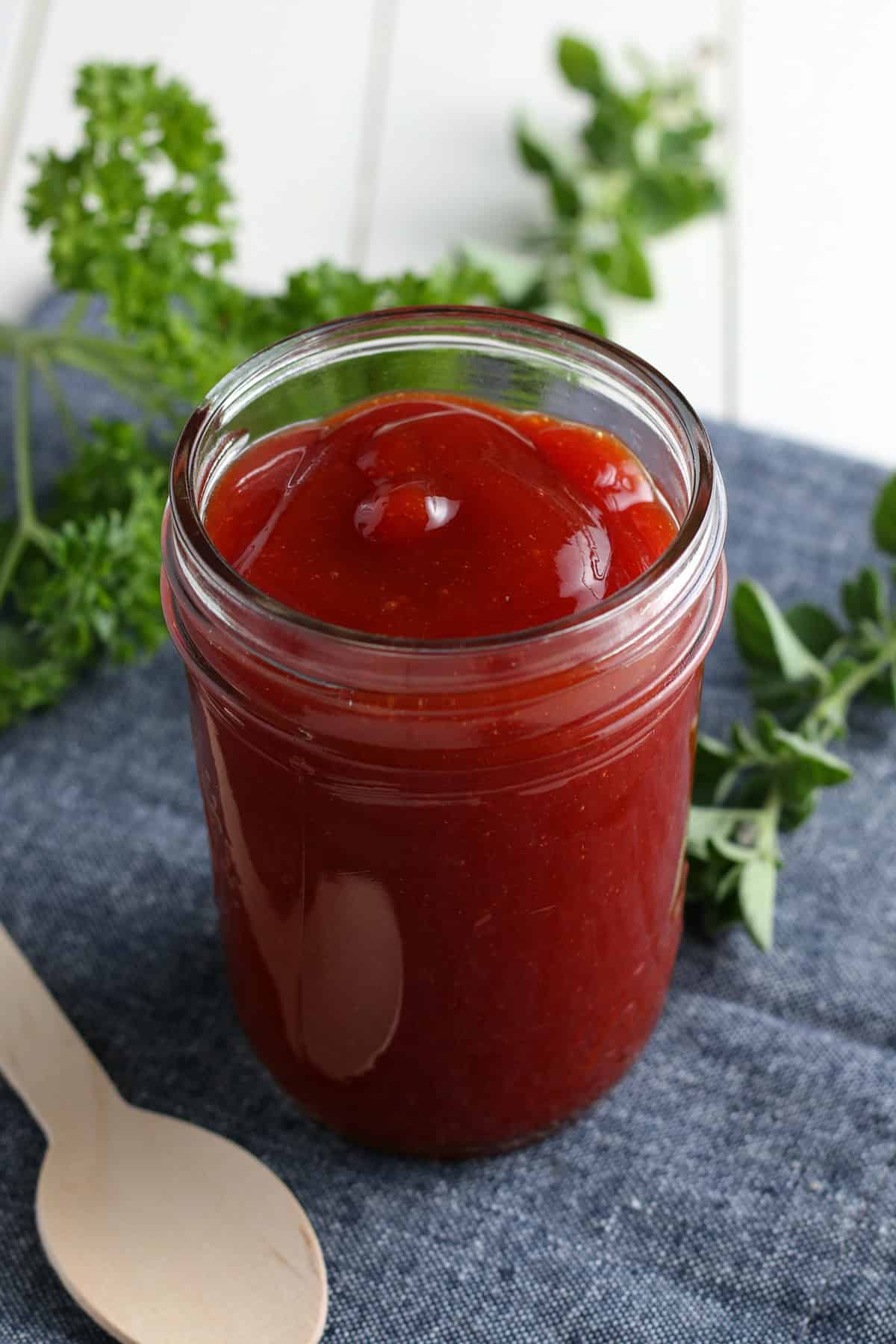 closeup photo showing a small glass jelly jar full of homemade barbecue sauce
