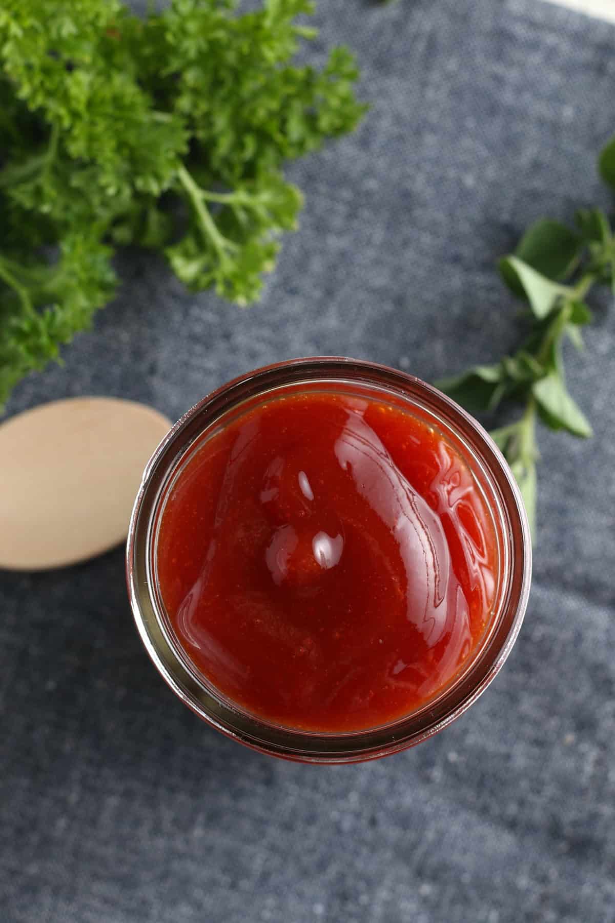 overhead photo showing small glass jelly jar full of easy homemade bbq sauce