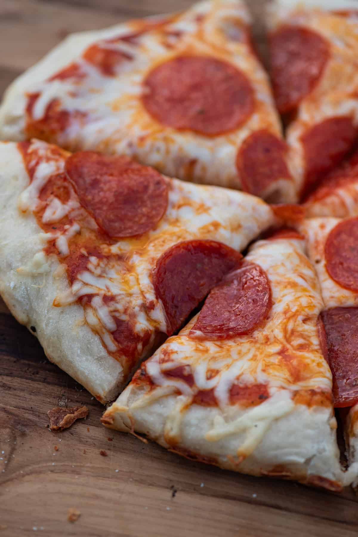 cast iron pepperoni pizza sliced up and ready to serve on a large wooden cutting board