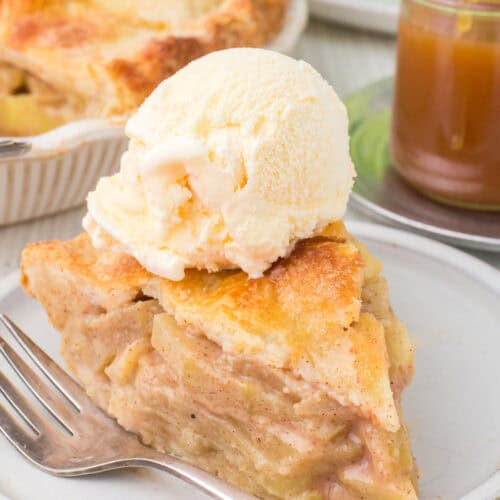 scoop vanilla ice cream on top of easy homemade apple pie slice on gray plate with fork