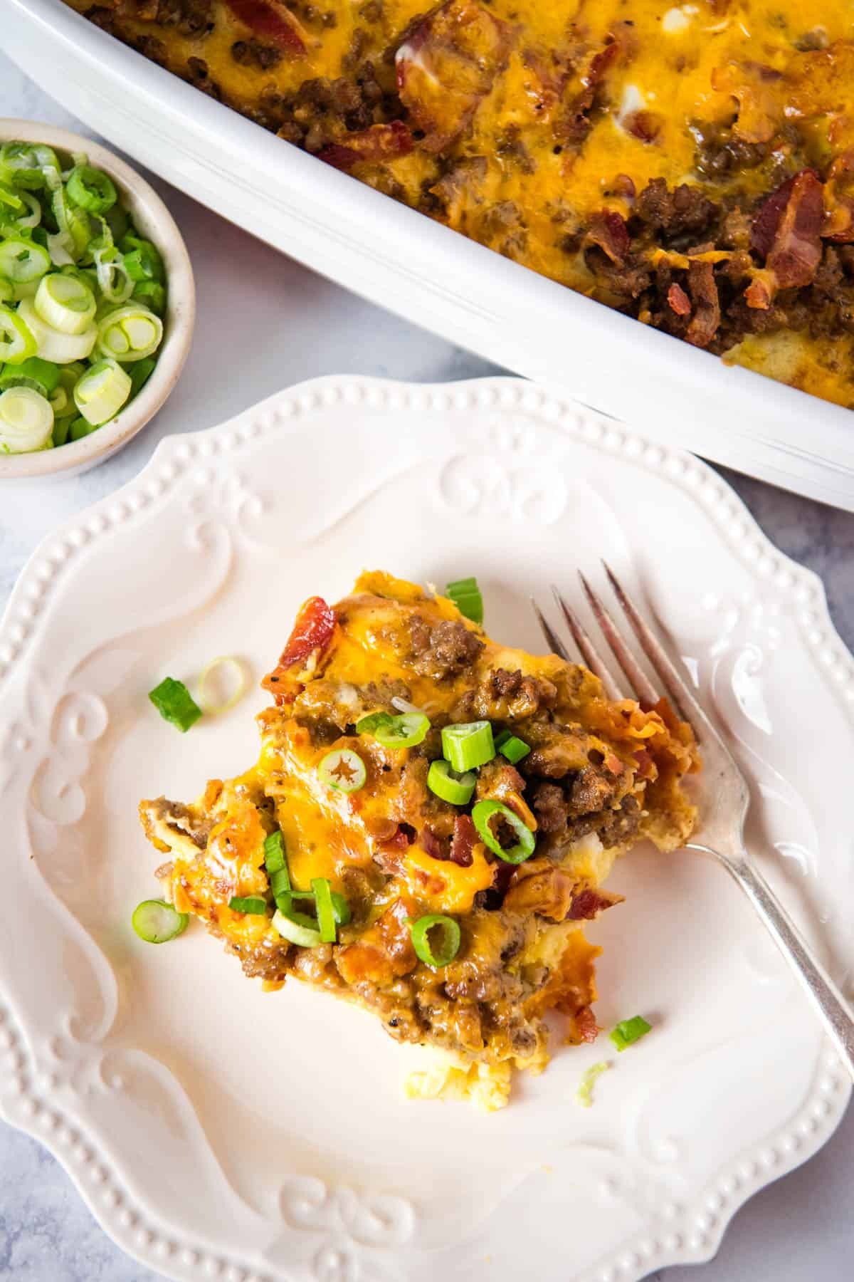 slice of breakfast casserole with texas toast on white plate with fork