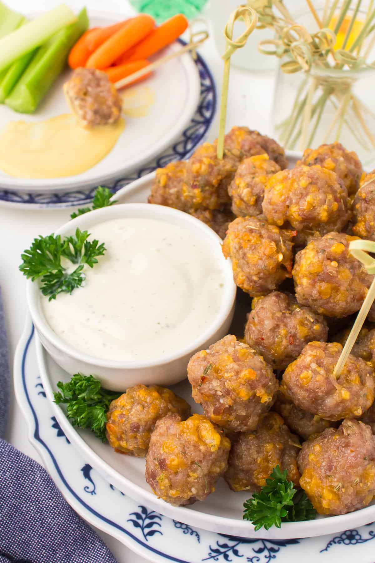 sausage cheese balls on a decorative blue and white plate with a small white ramekin full of ranch dressing for dipping